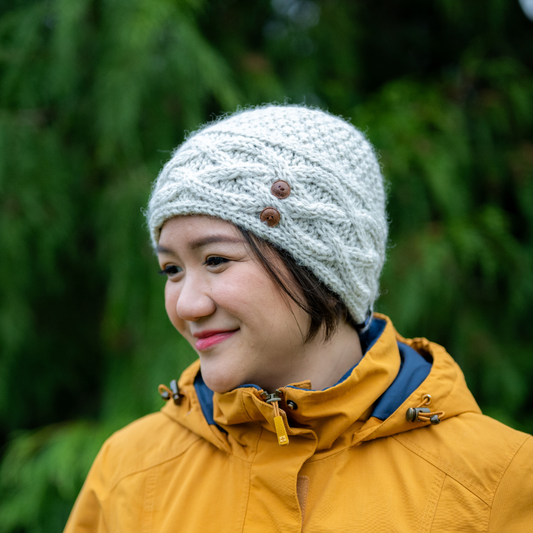 Woman wearing an Ambler Celtic handknit toque in heather stone with cable knit and buttons.