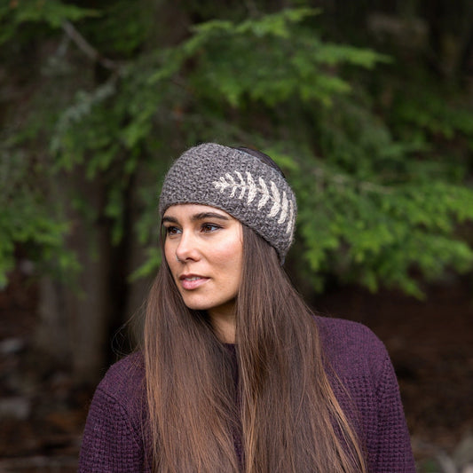 Woman wearing Ambler Ella handknit winter headband in heather grey with fern jacquard design.
