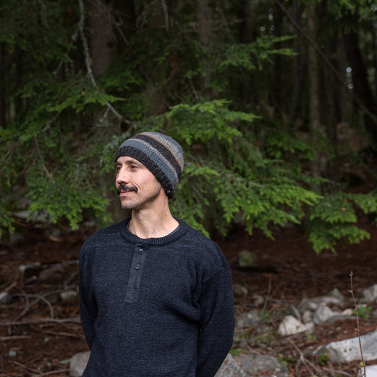 Man wearing Ambler Eric handknit wool men's toque in charcoal with tricolour striped pattern.
