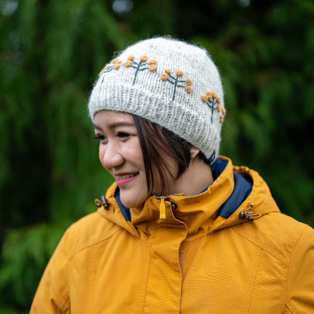 Woman wearing Ambler Marigold handknit women's toque in apricot with textured floral pattern.