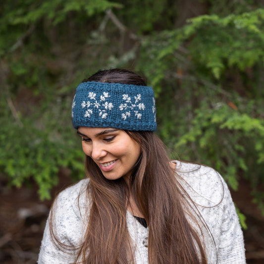 Woman wearing Ambler Stellar handknit winter headband in slate with snowflakes pattern and fleece lining.