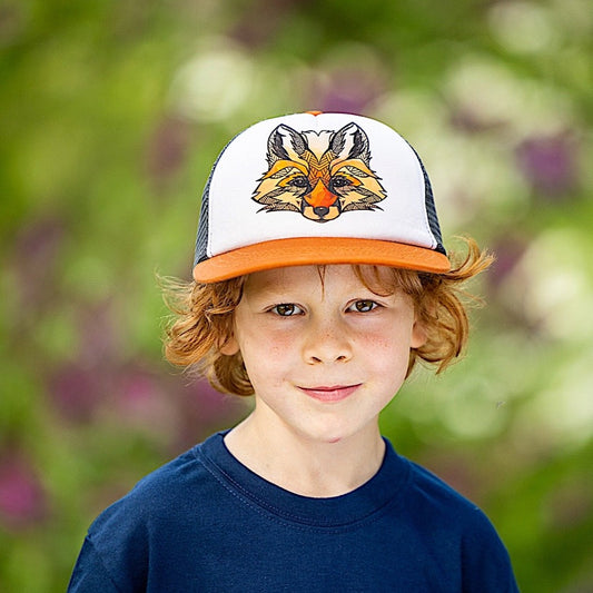 Boy wearing a kid's trucker hat with an orange brim, black back and orange fox face design on the white front panel.