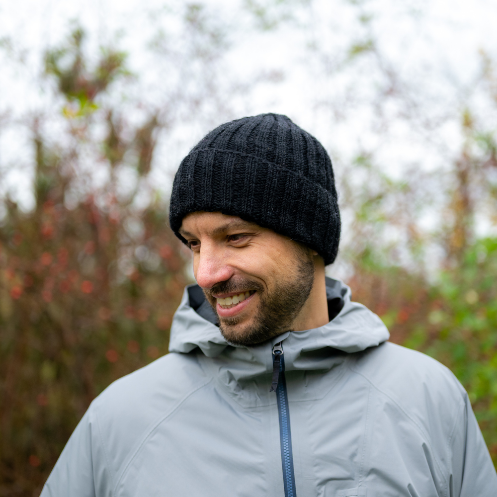 Man wearing Ambler Addison handknit wool men's toque in black with ribbed cuff and fleece headband lining. 
