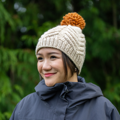 Woman wearing Ambler Audrey handknit women's toque in cream with orange medium pom.