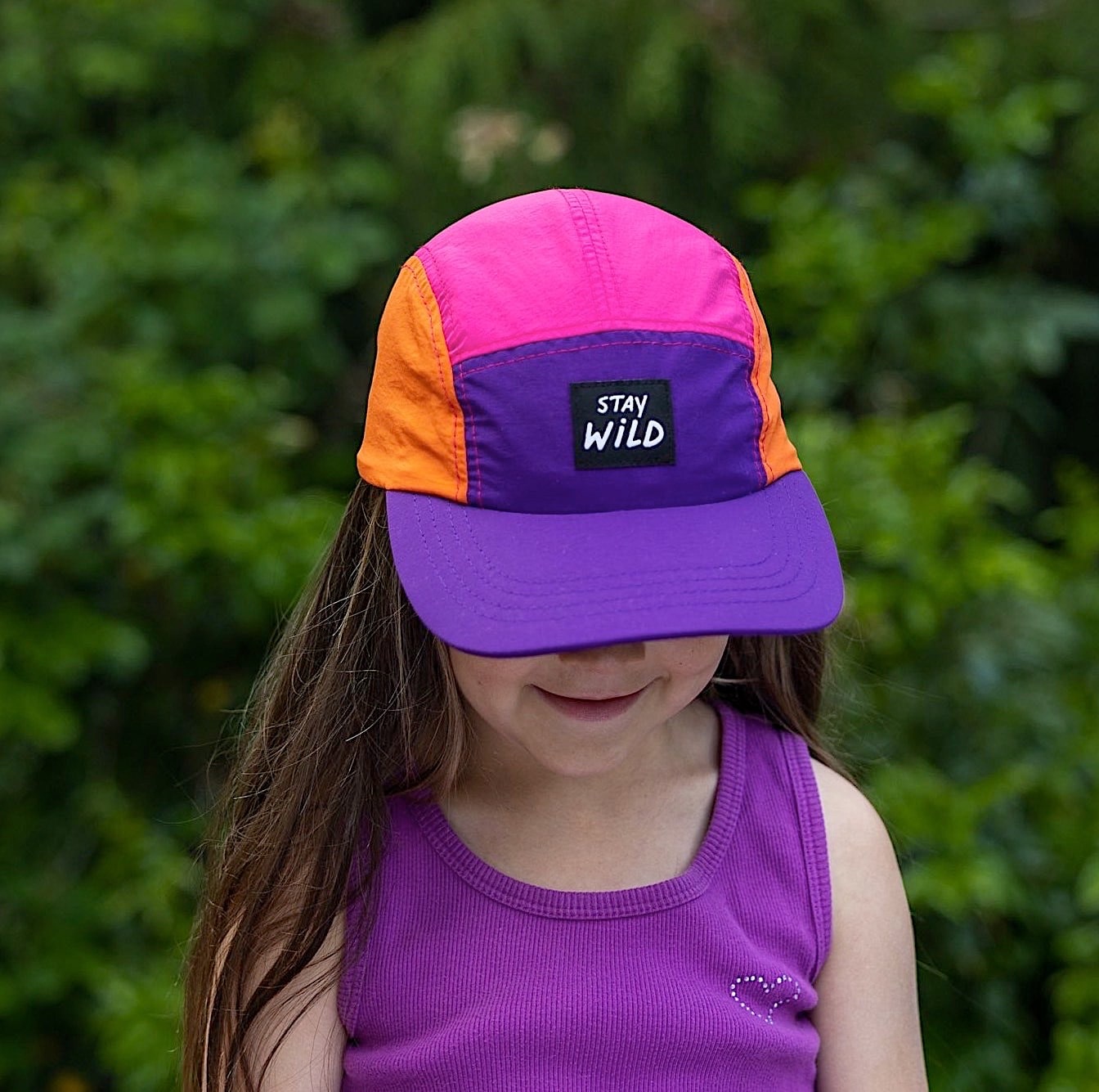 Girl wearing colorful blocked kids' 5 panel cap with 'Stay Wild' patch on the front panel. 