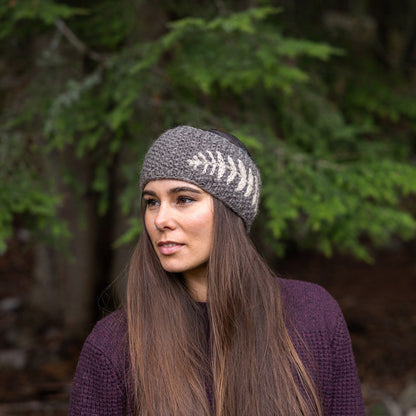 Woman wearing Ambler Ella handknit winter headband in heather grey with fern jacquard design.