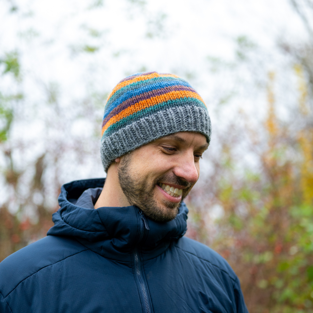 Man wearing Ambler Fiesta handknit men's toque in heather grey with striped design and ribbed cuff.  