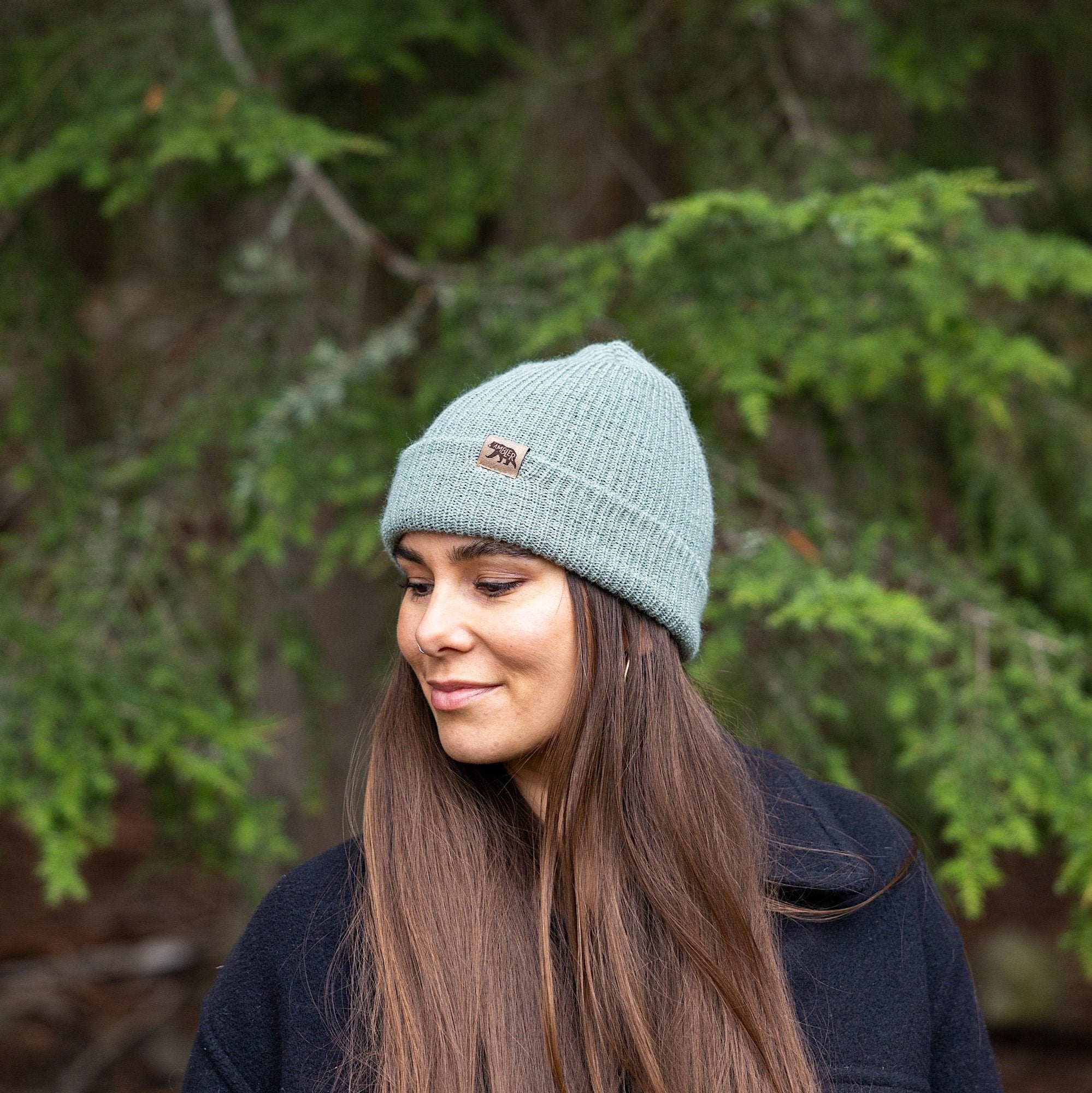 Woman wearing Made in Canada Ambler Hawken machine knit toque in willow with faux leather bear clip. 