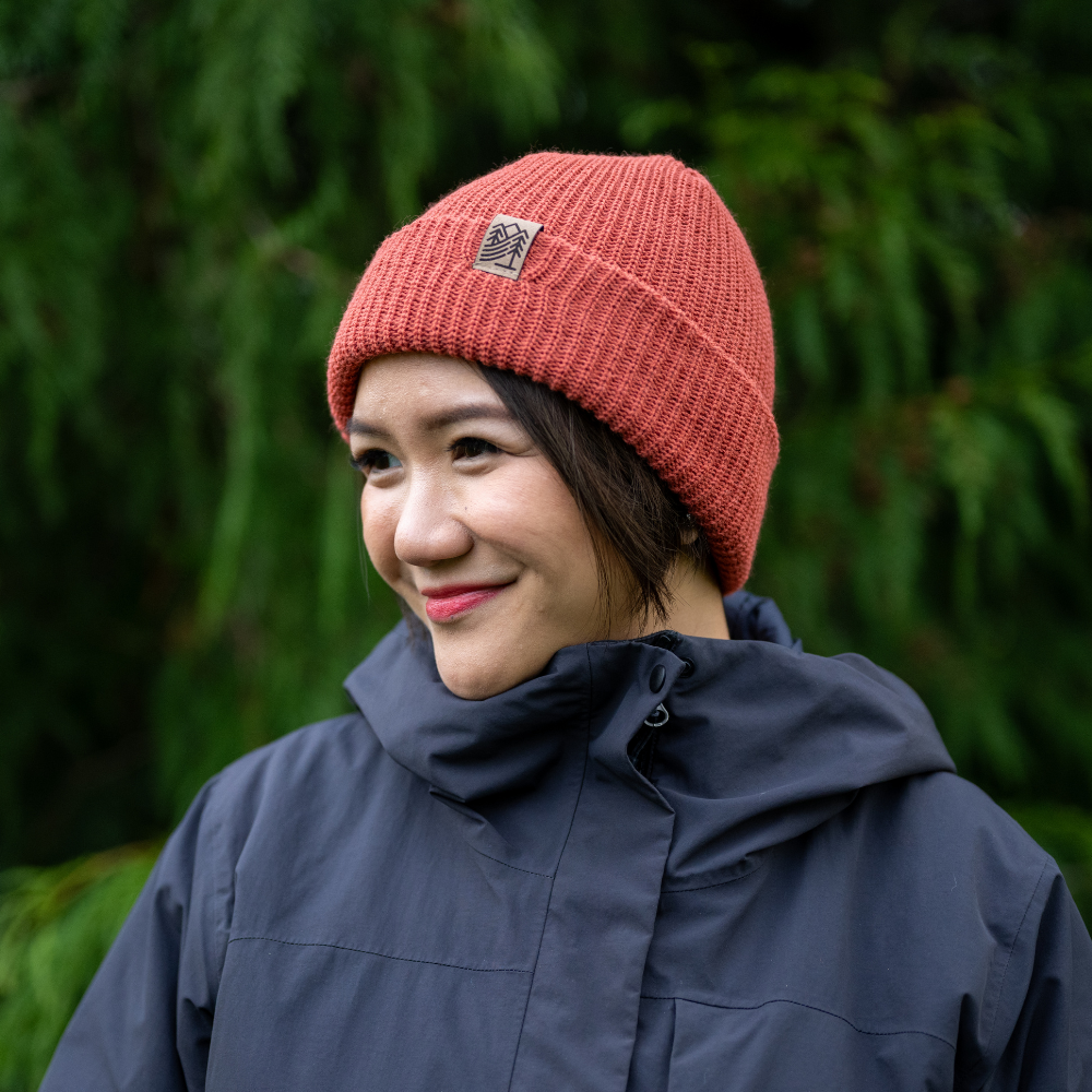 Woman wearing Made in Canada Ambler Hawken machine knit toque in terracotta with faux leather bear clip. 