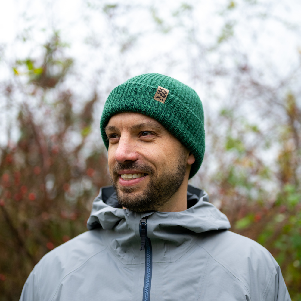 Man wearing Made in Canada Ambler Hawken machine knit toque in verte with faux leather bear clip. 
