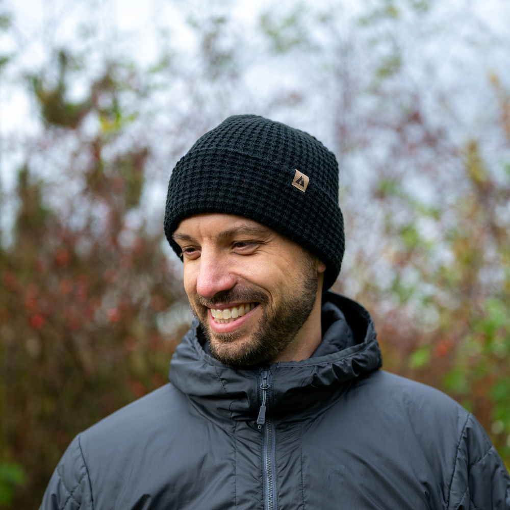 Man wearing Made in Canada Ambler honeycomb machine knit toque in black with faux leather brand clip. 