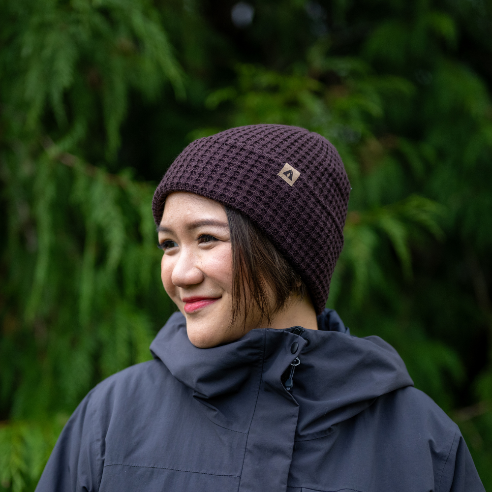 Lady wearing Made in Canada Ambler honeycomb machine knit toque in blackberry with faux leather brand clip. 