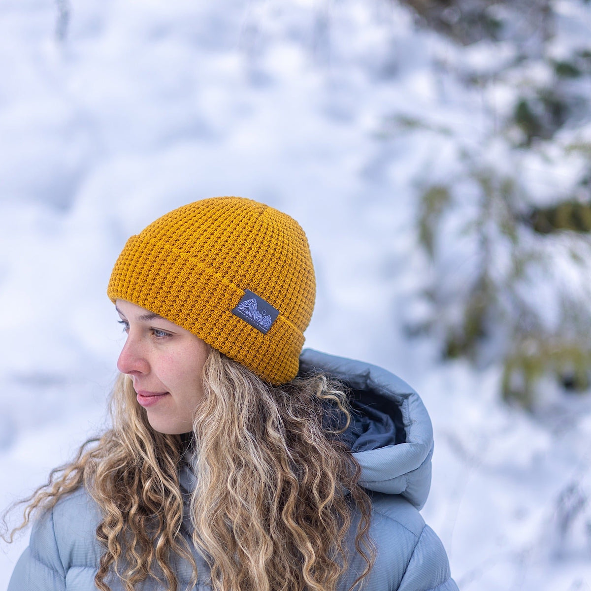 Woman wearing Made in Canada Ambler Joffre machine knit toque in bronze. 