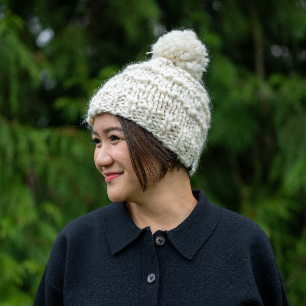 Woman wearing Ambler Madison handknit 100% wool women&#39;s toque in natural with pom. 