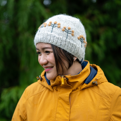 Woman wearing Ambler Marigold handknit women's toque in apricot with textured floral pattern. 