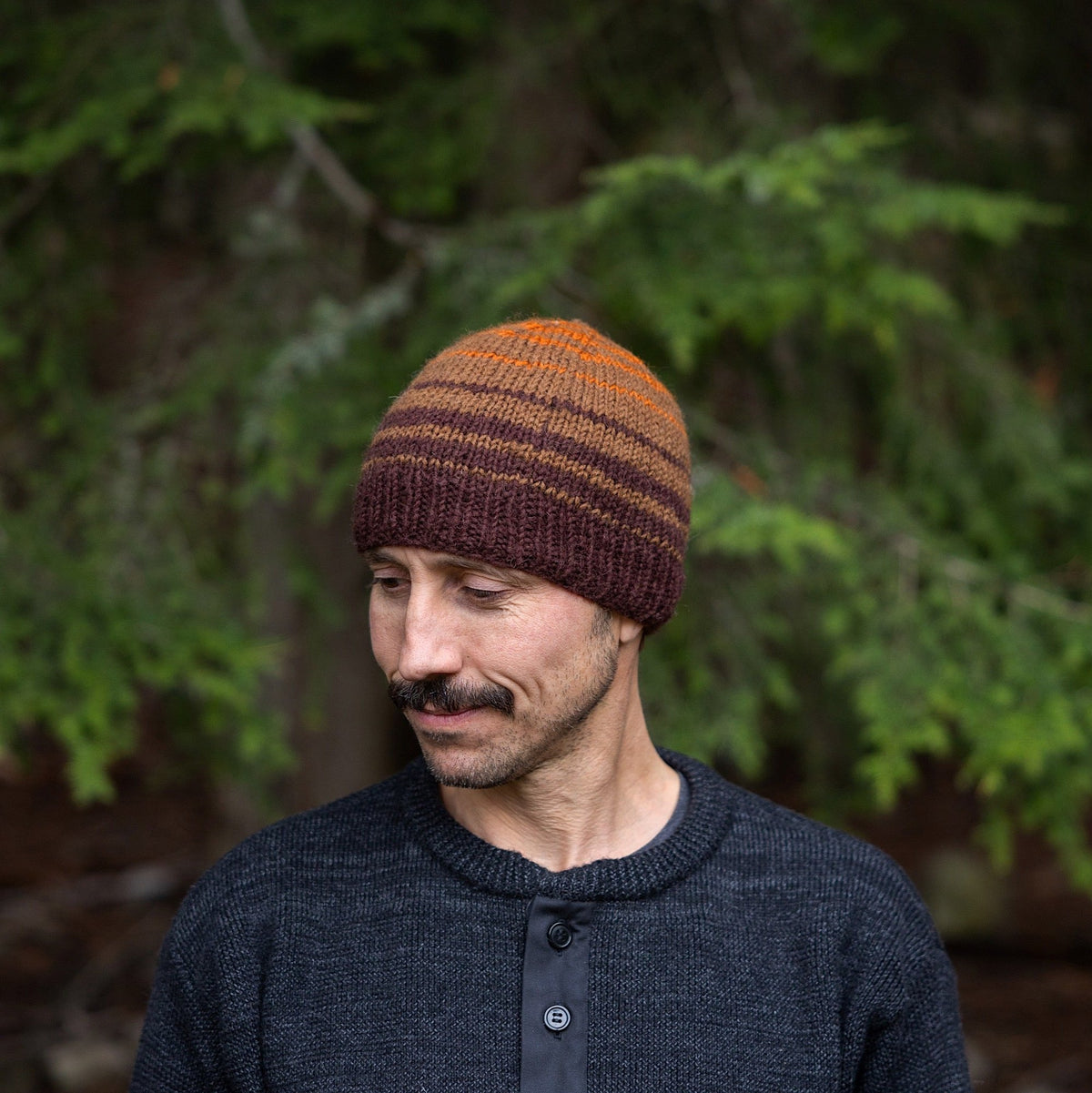 Man wearing Ambler Ollie handknit wool men&#39;s toque in espresso with striped design and warm ribbed cuff. 