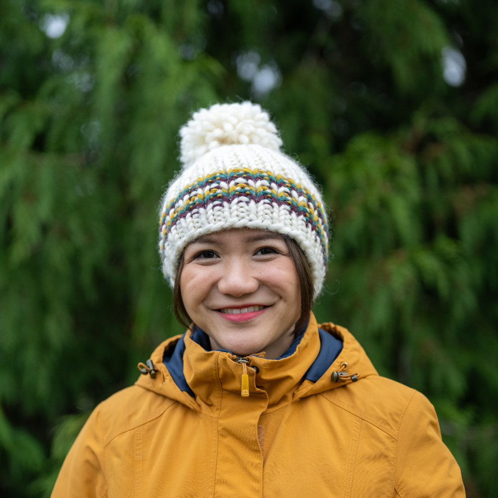 Woman wearing Ambler Parker handknit wool women&#39;s toque in citrus - thick rib and medium pom. 