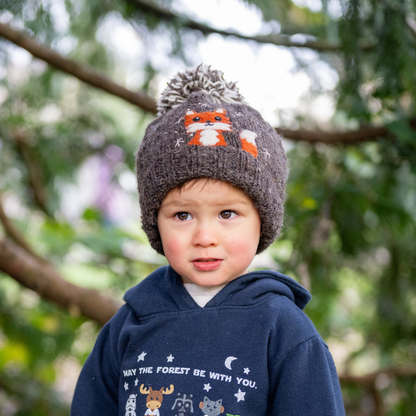 Boy wearing Ambler Peek-A-Boo handknit kids' toque in heather brown with felted fox character and duotone pom.