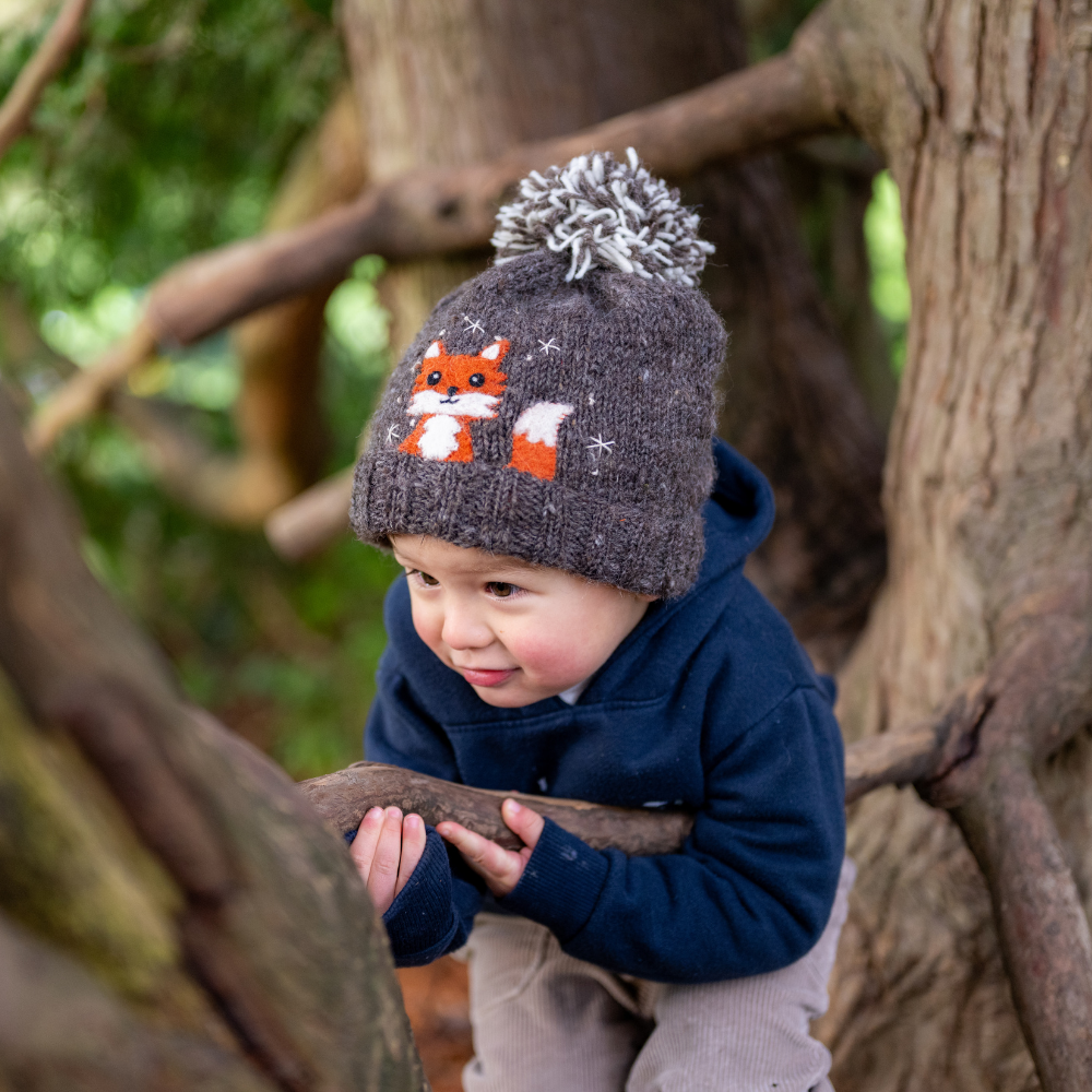 Boy wearing Ambler Peek-A-Boo handknit kids&#39; toque in heather brown with felted fox character and duotone pom.