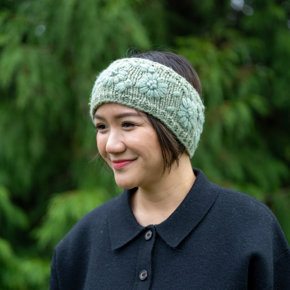Woman wearing Ambler Petal handknit wool headband in ice green with monotone floral pattern. 