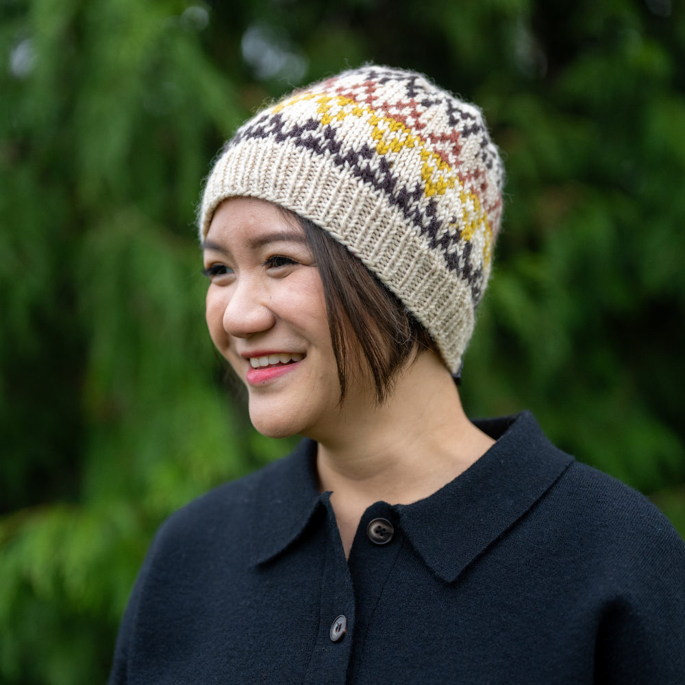 Woman wearing Ambler Prism handknit wool women's toque in cream with jacquard knit design and ribbed cuff. 