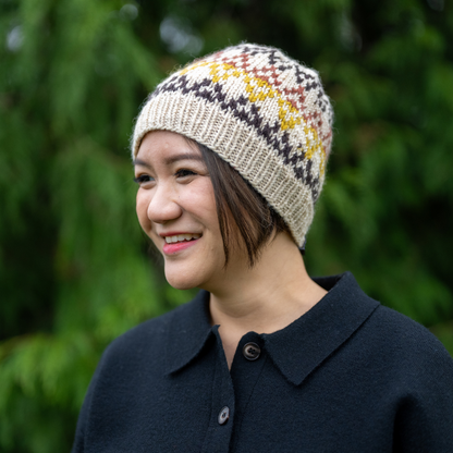 Woman wearing Ambler Prism handknit wool women's toque in cream with jacquard knit design and ribbed cuff. 
