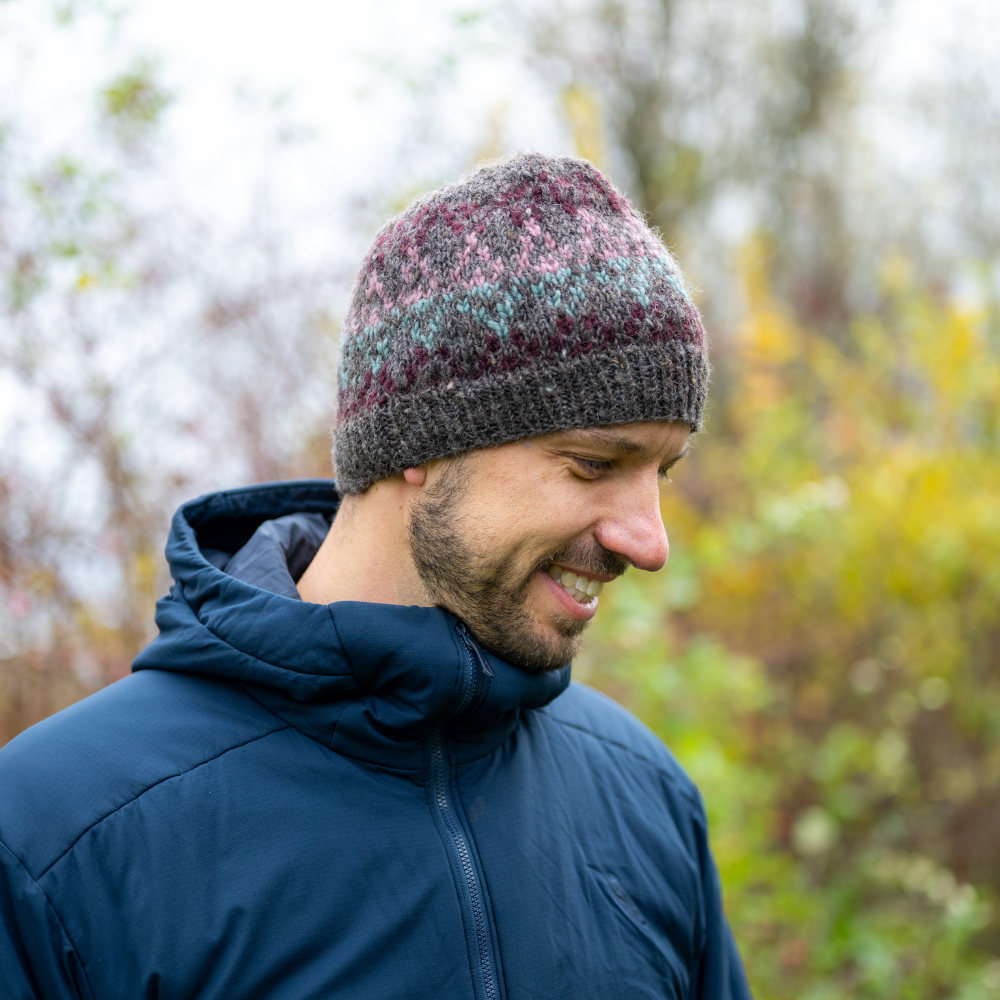 Man wearing Ambler Prism handknit wool women's toque in heather brown with jacquard knit design and ribbed cuff. 