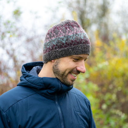 Man wearing Ambler Prism handknit wool women's toque in heather brown with jacquard knit design and ribbed cuff. 
