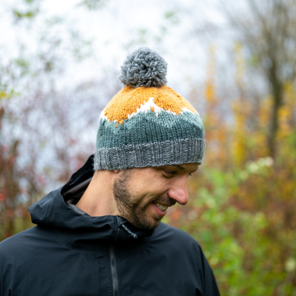 Man wearing Ambler Purcell handknit toque in heather grey with mountain jacquard design and ribbed band. 
