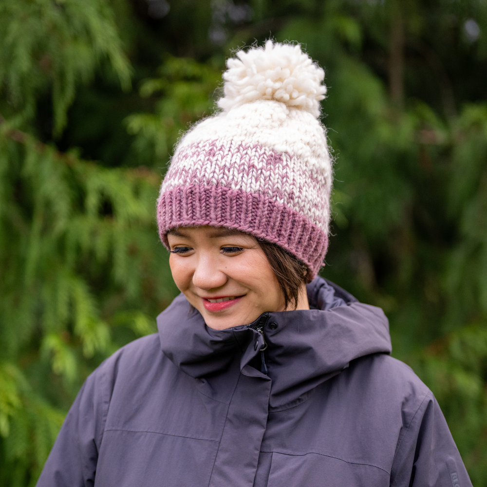 Woman wearing Ambler Wren handknit women&#39;s toque in wild ginger with ribbed cuff and medium pom. 