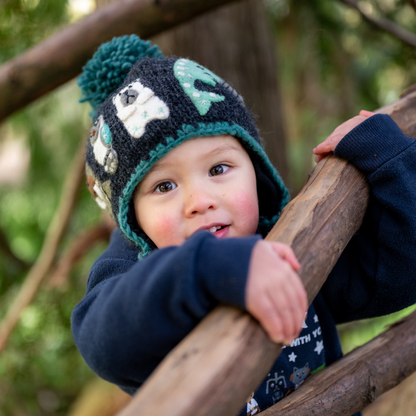 Toddler wearing Ambler Yeti handknit kids' toque in heather charcoal with felted creatures and medium pom. 
