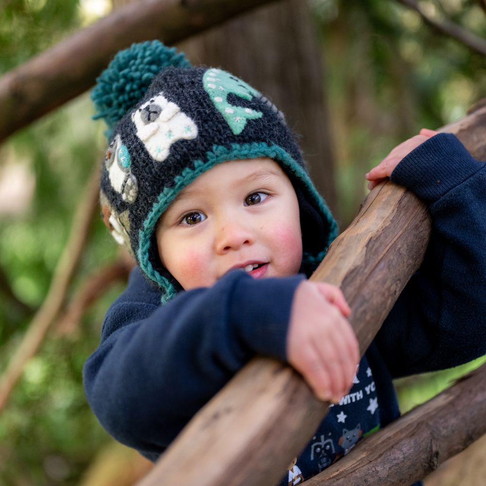 Toddler wearing Ambler Yeti handknit kids&#39; toque in heather charcoal with felted creatures and medium pom. 